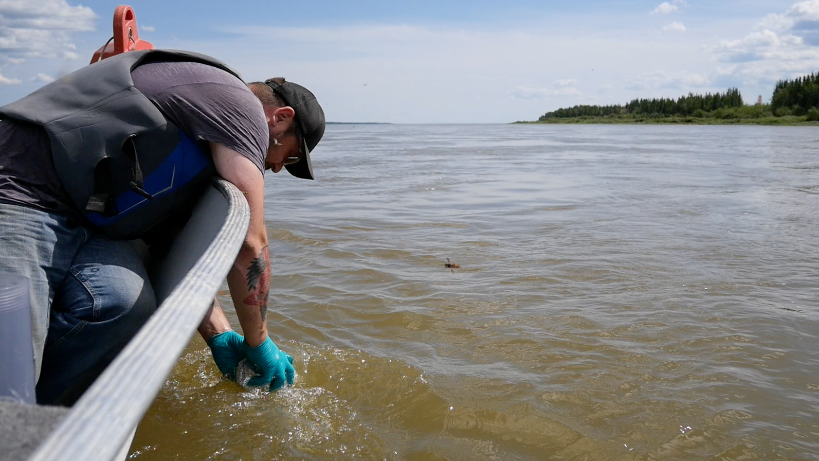 Mike Low, AAROM (Aboriginal Aquatic Resources & Ocean Management) Program Coordinator with Dehcho First Nations, collecting a water sample from a boat.