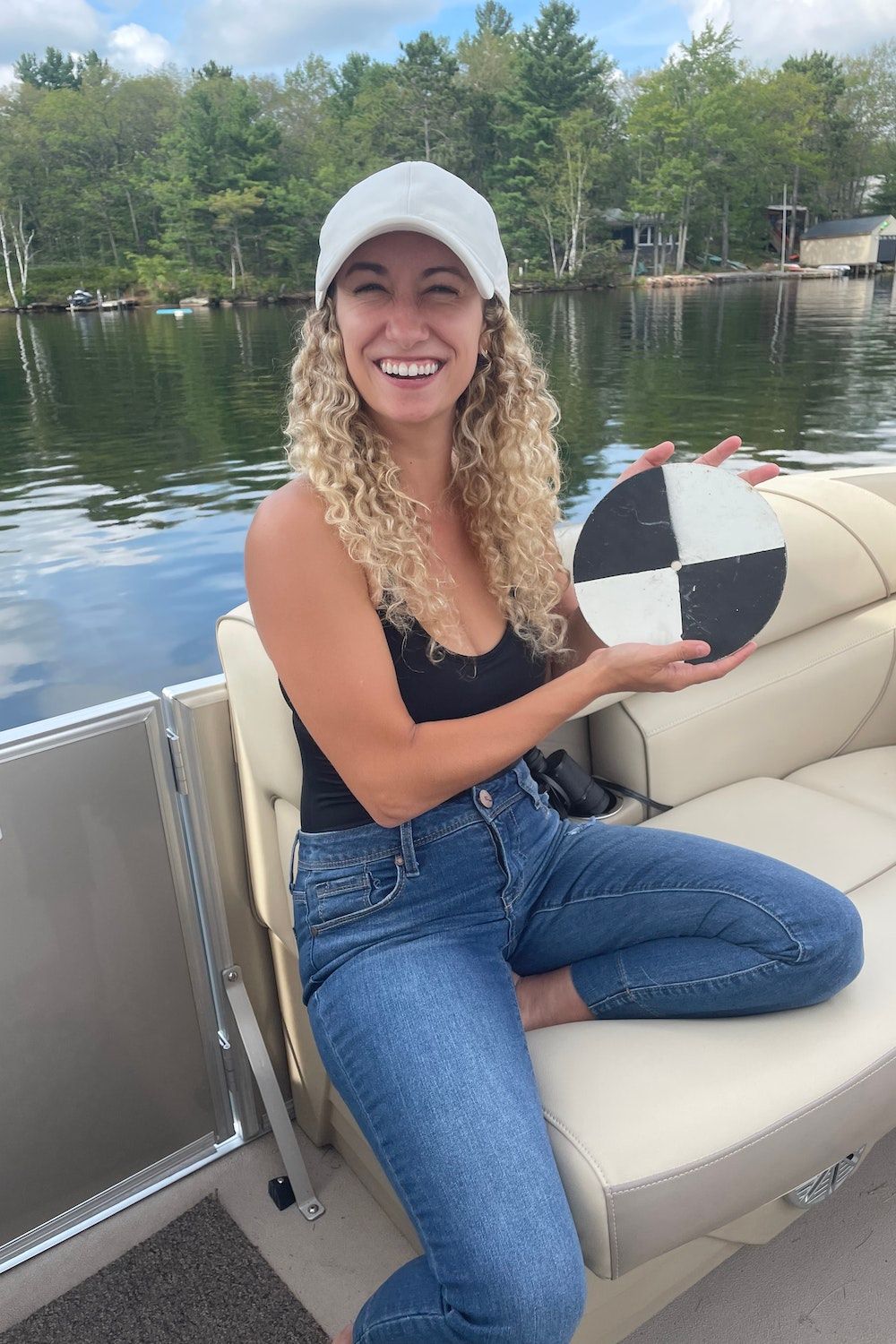 Liz Favot souriante est assise sur un bateau tenant un disque secchi