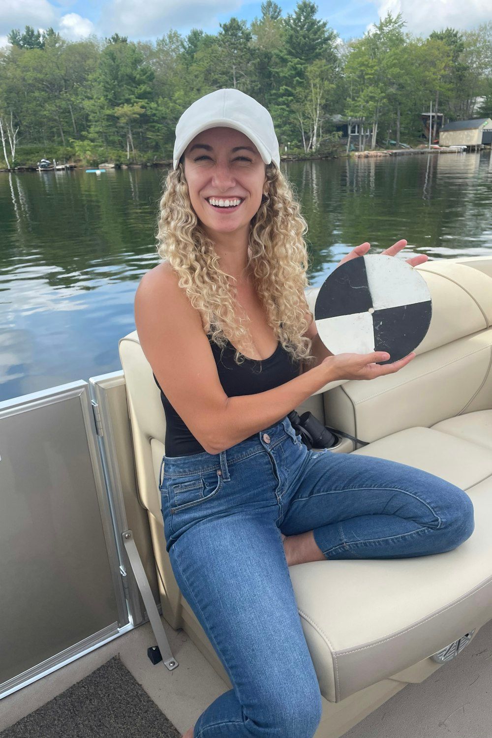 Liz Favot sits on a boat holding a secchi disk
