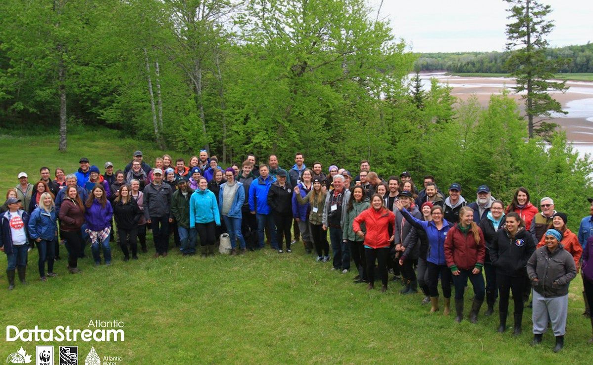 Group of Atlantic Canadian community based water monitoring groups standing for a photo on a field next to a river