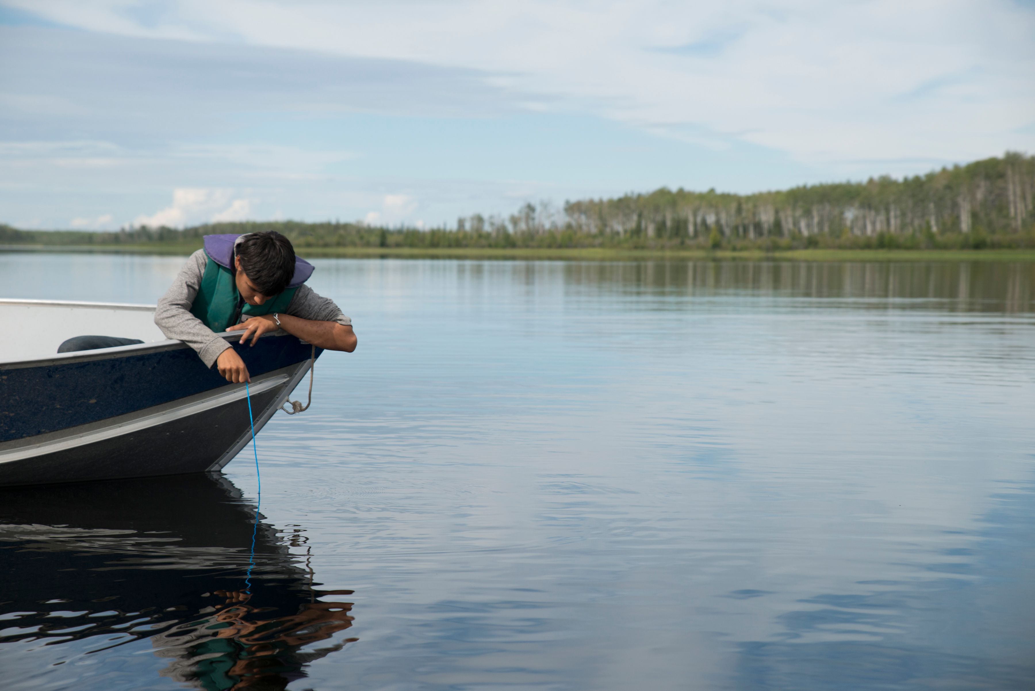 A youth monitors the water as part of a community-based monitoring program in the Northwest Territories.