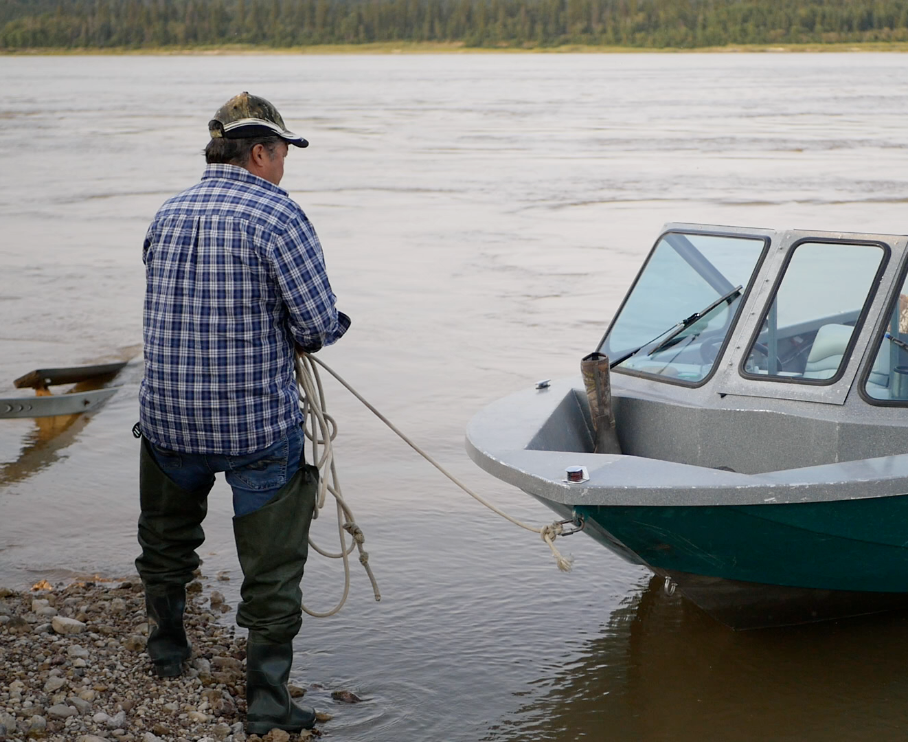 A local man stands ashore with his boat in the water in NWT.
