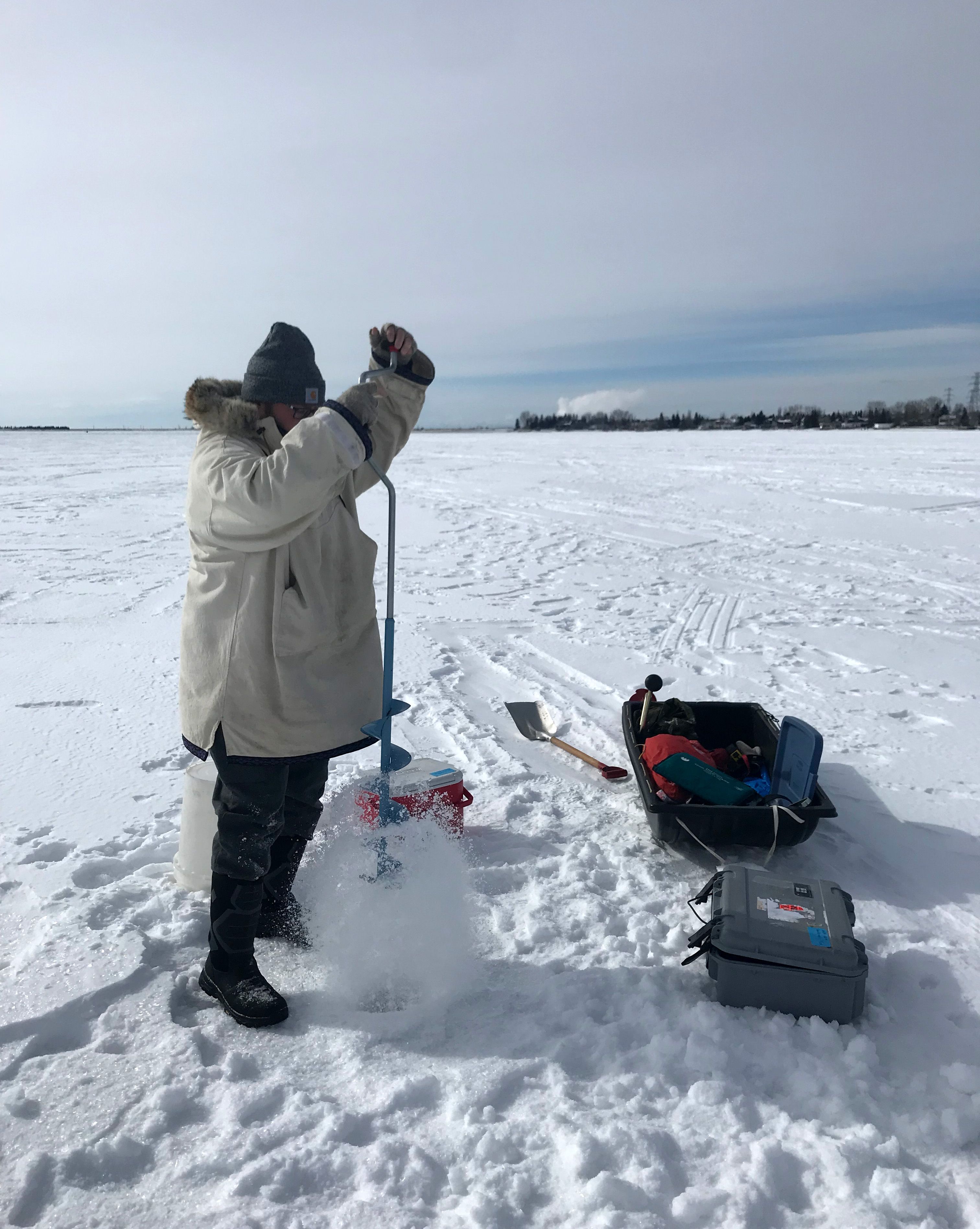 LakeKeepers volunteer Rick Robinson using an auger to drill a hole in Chestermere Lake.