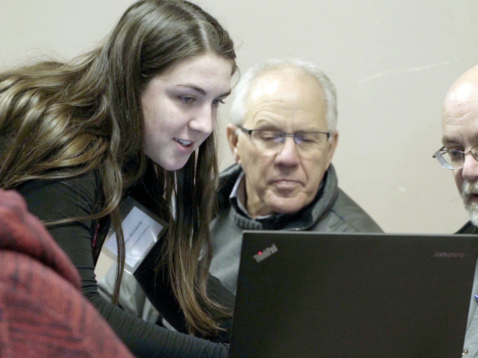 Woman showing two men datastream on a laptop