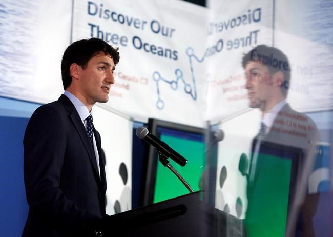 Justin Trudeau speaking at a podium with a banner reading Discover Our Three Oceans in the background