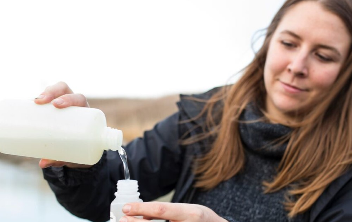 Chelsea Lobson (Lake Winnipeg Foundation) verse de l'eau dans une bouteille d'échantillon.